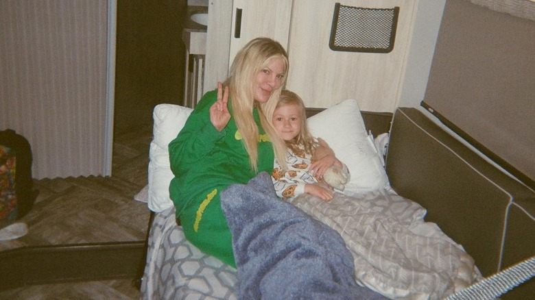 Tori Spelling making peace sign with kid