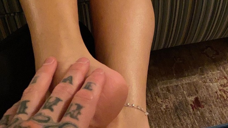 Barker holding Kardashian's foot