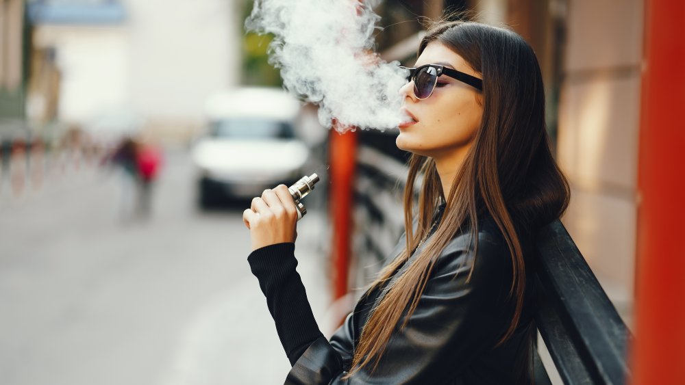 A woman vaping in a city environment