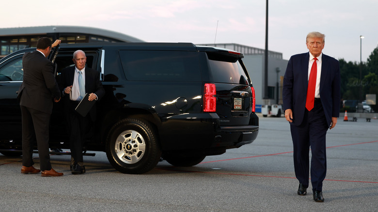 Steven Sadow getting out of a car behind Donald Trump