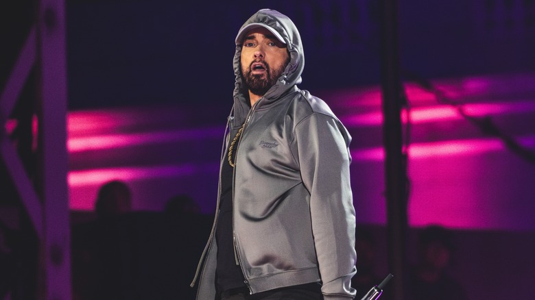 Eminem performing onstage in a grey hoodie