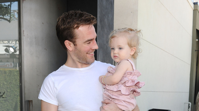 James Van Der Beek smiling and holding daughter Olivia in 2012