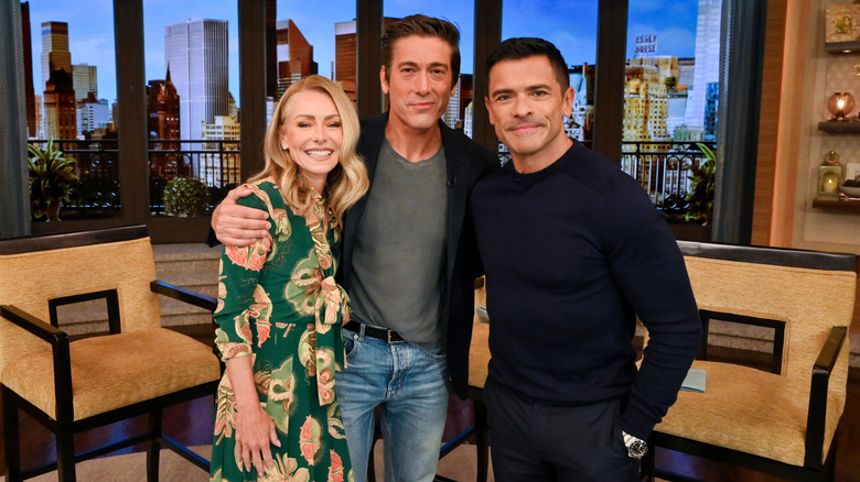 Kelly Ripa, David Muir, and Mark Consuelos smiling on the set of Live With Kelly and Mark in September 2024