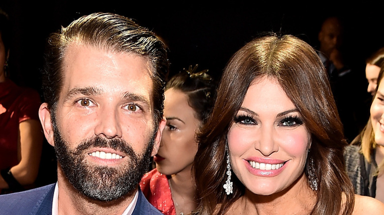 Donald Trump Jr. and Kimberly Guilfoyle sitting together and smiling at an event