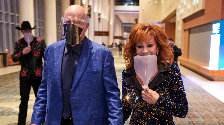 Reba McEntire and Rex Lin hold hands at an event.