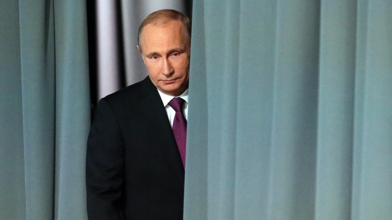 Vladimir Putin emerges from behind a curtain