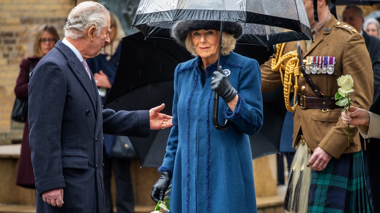 Queen Camilla holding umbrella in the rain