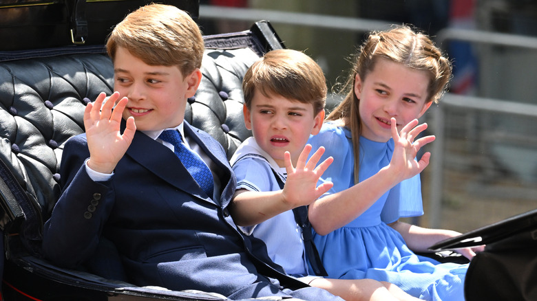 Prince George, Prince Louis, and Princess Charlotte waving from a carriage 