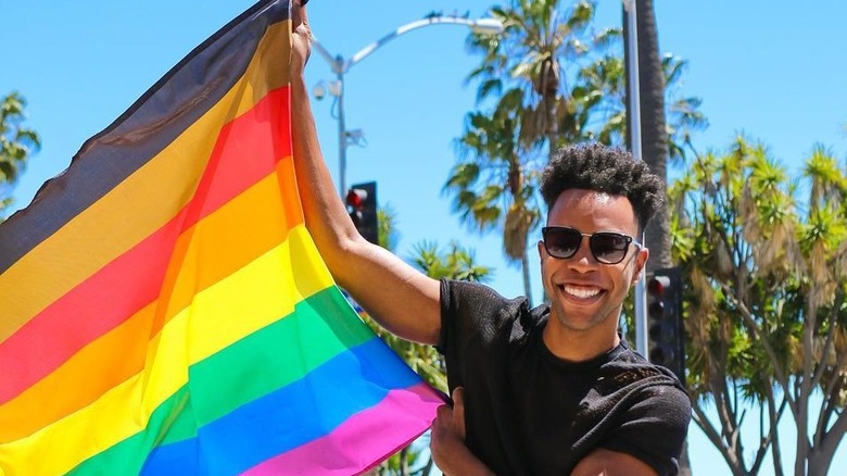 Emile Ennis Jr. waving an inclusive Pride flag