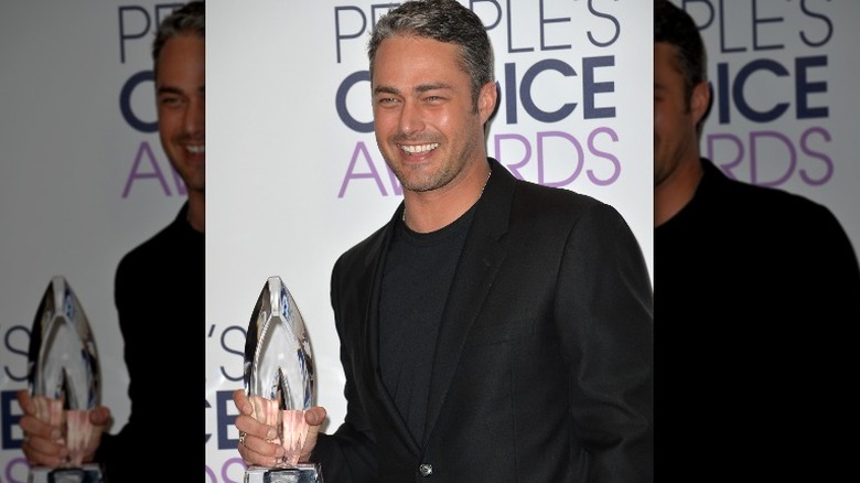 Taylor Kinney holding award