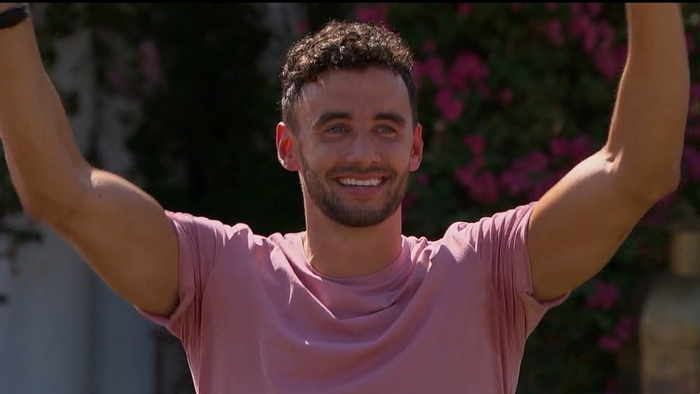 Brendan Morais in a pink shirt, arms raised