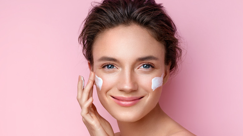 A woman applying moisturizer on her face