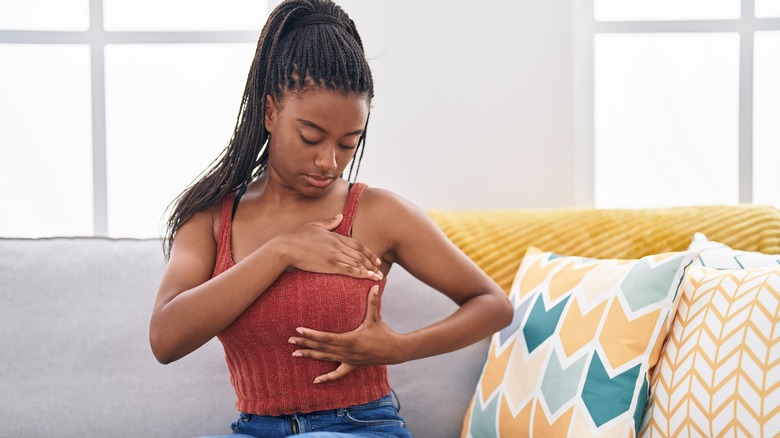 Woman inspecting her breast for signs of cancer