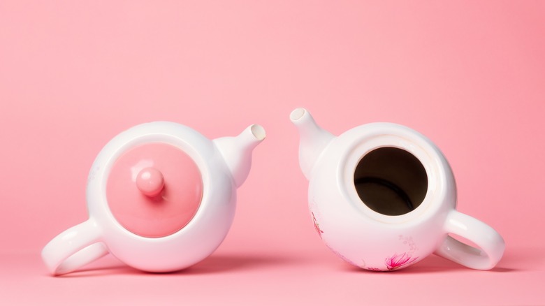 Two teapots depicting a woman's breasts. One is missing a lid.