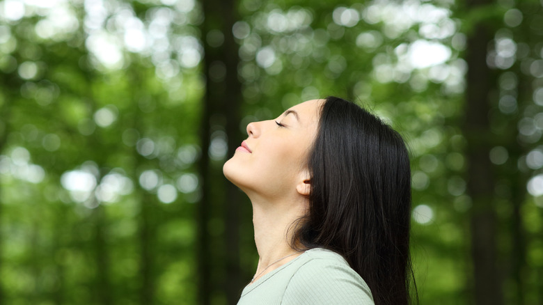 Woman standing in a forest thinking 