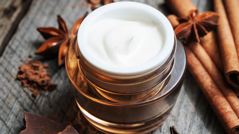 A jar of cocoa butter with chocolate and cinnamon around it