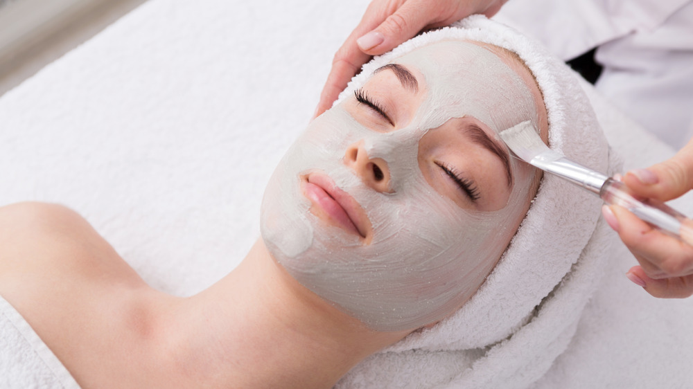 Woman with clay mask treatment