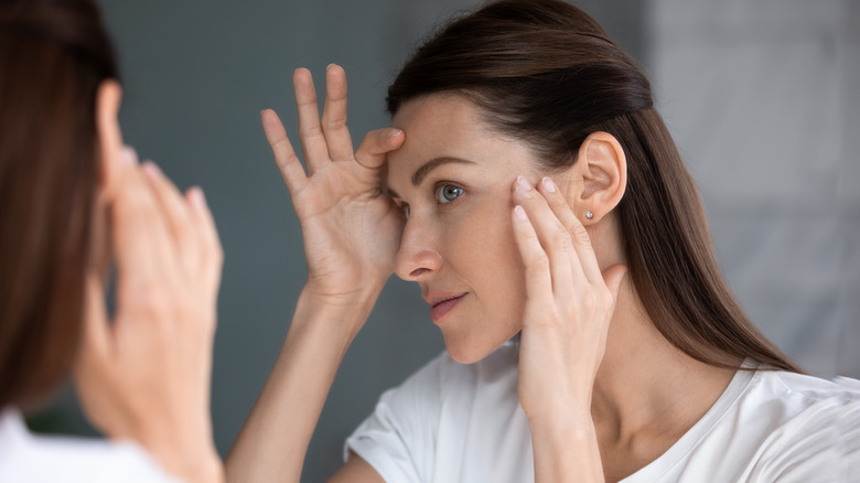 A woman checking her face in front of the mirror.