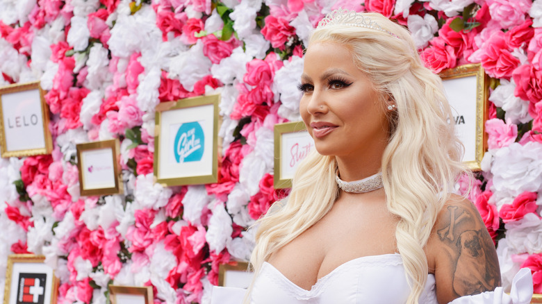 Amber Rose posing by flowered backdrop