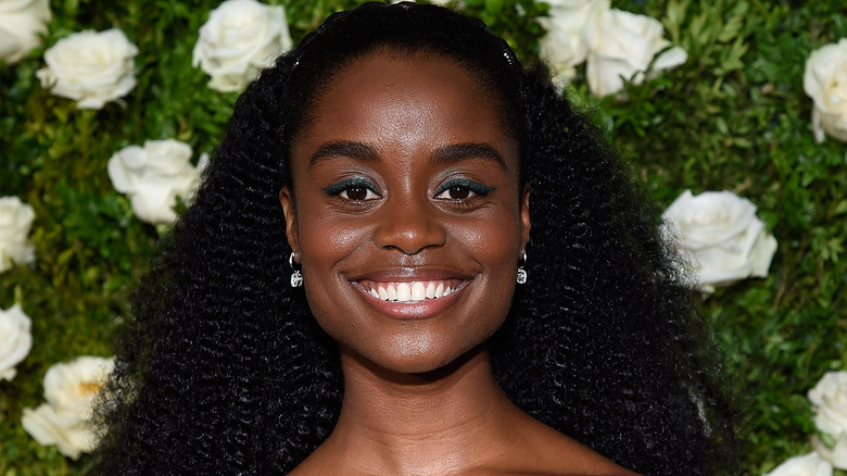 Denée Benton smiling, floral backdrop