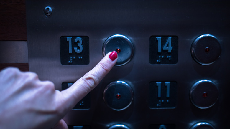 Woman presses the button for the 13th floor on an elevator