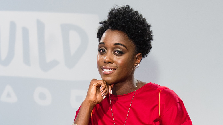 Lashana Lynch sitting