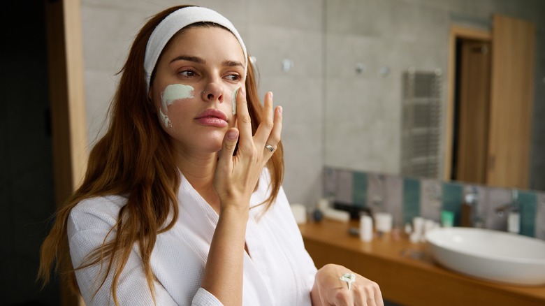 Woman applying exfoliating scrub in mirror