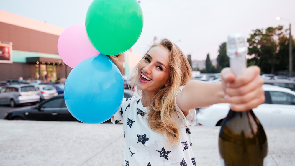 Woman holding champagne and balloons