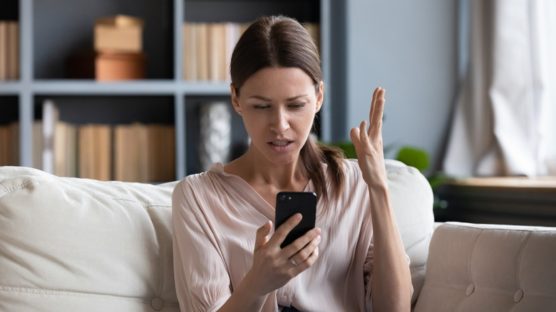 Woman looking at phone, upset