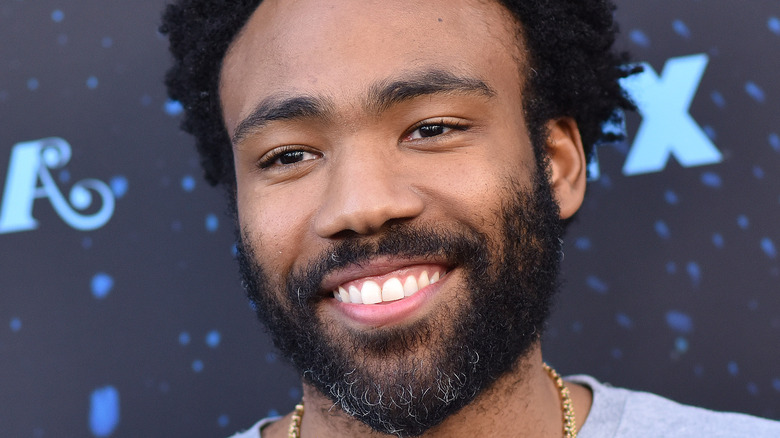 Donald Glover smiling at a press event.