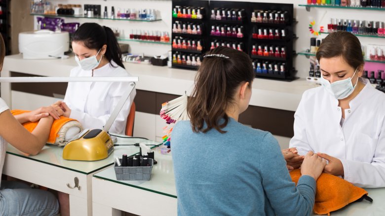 nail technicians doing nails while wearing masks