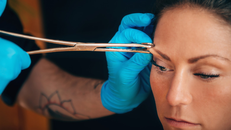 Woman getting her eyebrow pierced