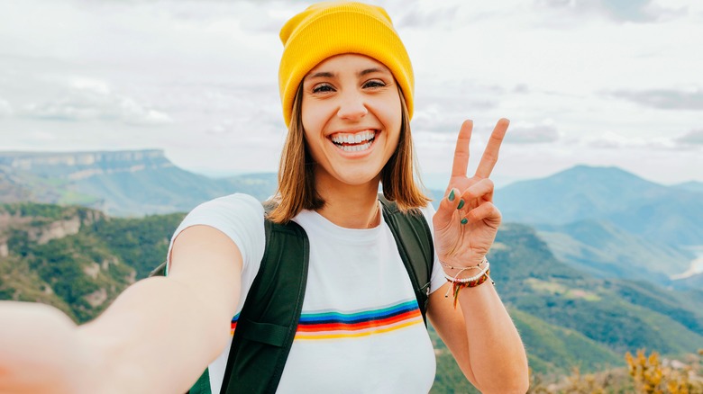 Woman poses for selfie with a peace sign