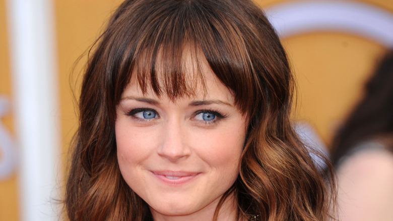 Alexis Bledel smiling with closed lips on the red carpet with her hair down.