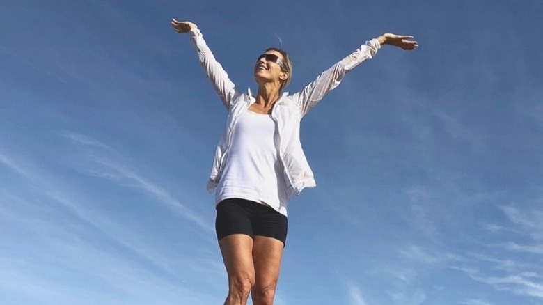 Candice Olson outdoors with arms raised in victory