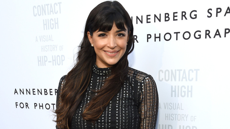 Hannah Simone smiling on step-and-repeat