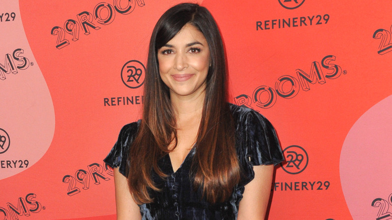 Hannah Simone smiling on step-and-repeat