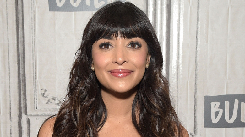 Hannah Simone smiling on step-and-repeat