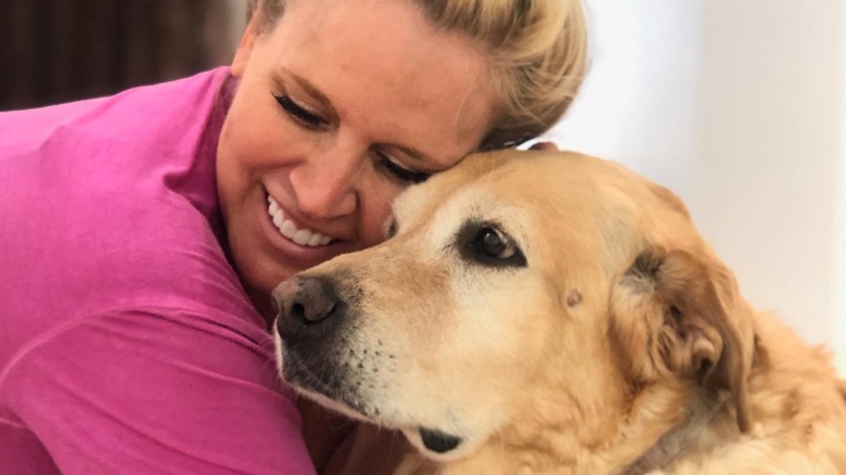 Paige Hemmis smiles while hugging her dog.