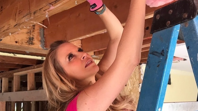 Paige Hemmis looks towards ceiling during house renovations wearing pink gloves