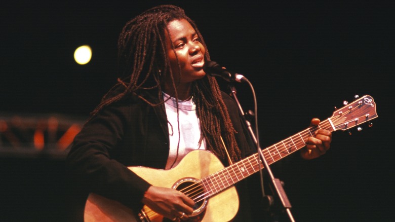 Tracy Chapman holds guitar and sings onstage