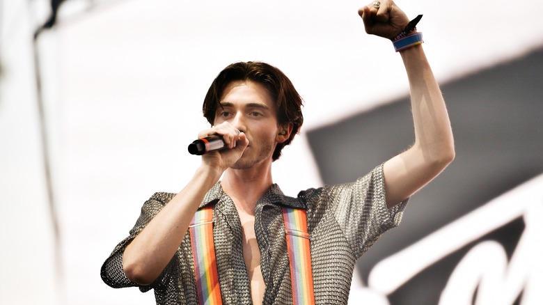 Greyson Chance wearing rainbow suspenders, raising his fist