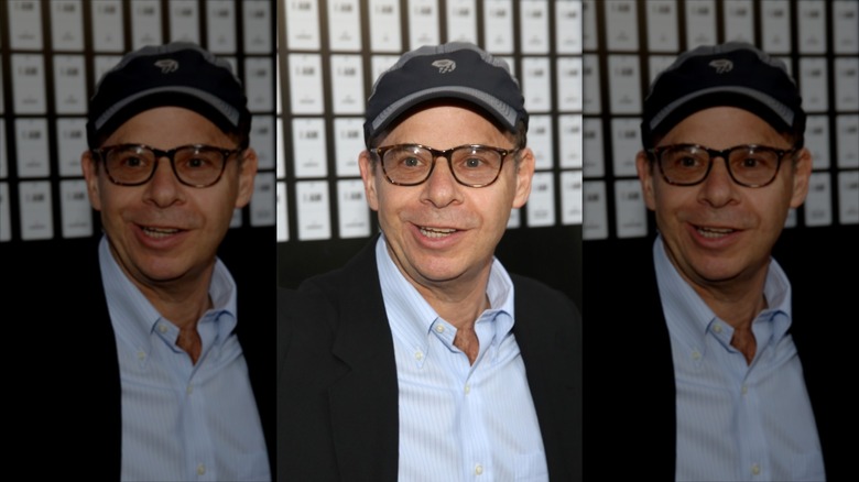 Rick Moranis smiling in a baseball cap