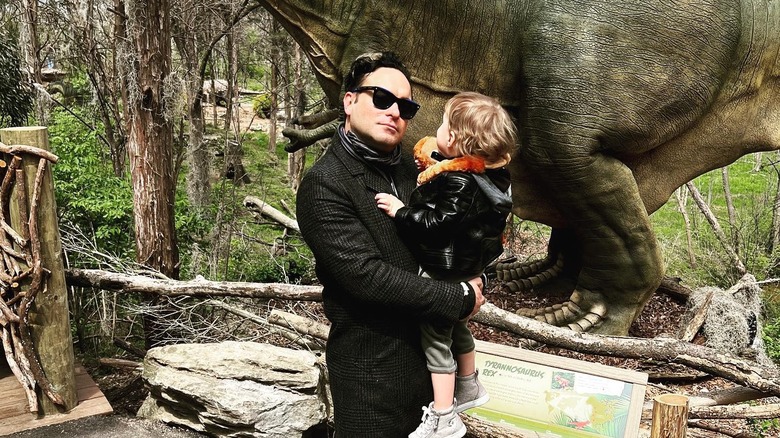 Johnny Galecki holding his son while wearing glasses