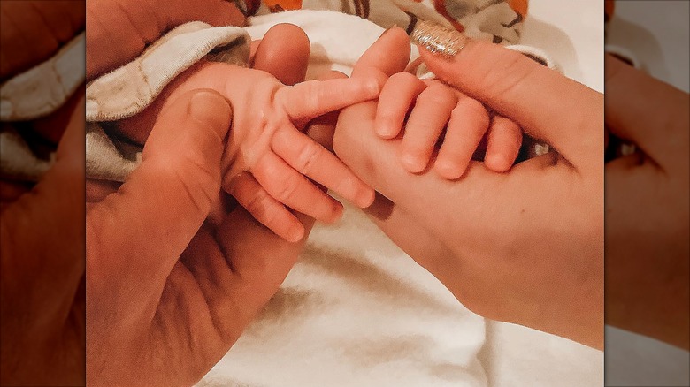 Johnny Galecki and his girlfriend holding his son's fingers