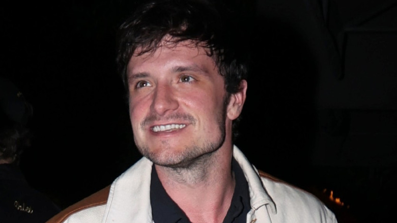 Josh Hutcherson looking away smiling on a street