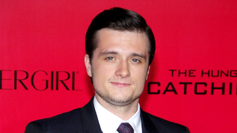 Josh Hutcherson standing against a red background at the Hunger Game: Catching Fire