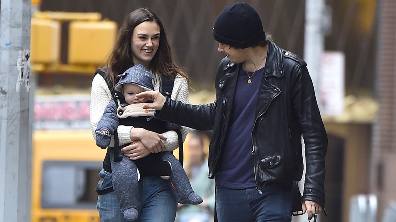 Keira Knightley carrying a child with her husband on the street