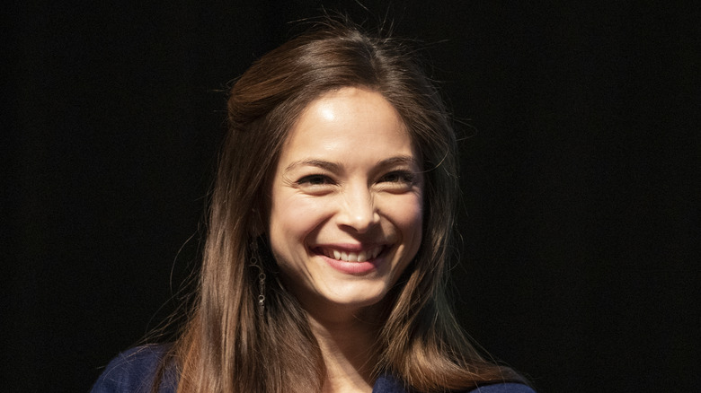 Kristin Kreuk smiling against a black background