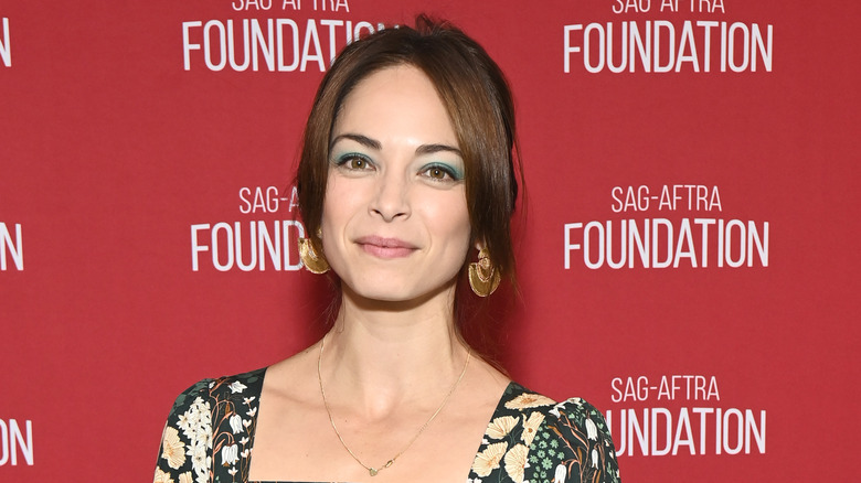 Kristin Kreuk standing against a red background